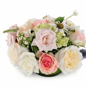 Pastel rose and hydrangea floral arrangement with pink, cream, and peach tones, photographed on a pure white background.